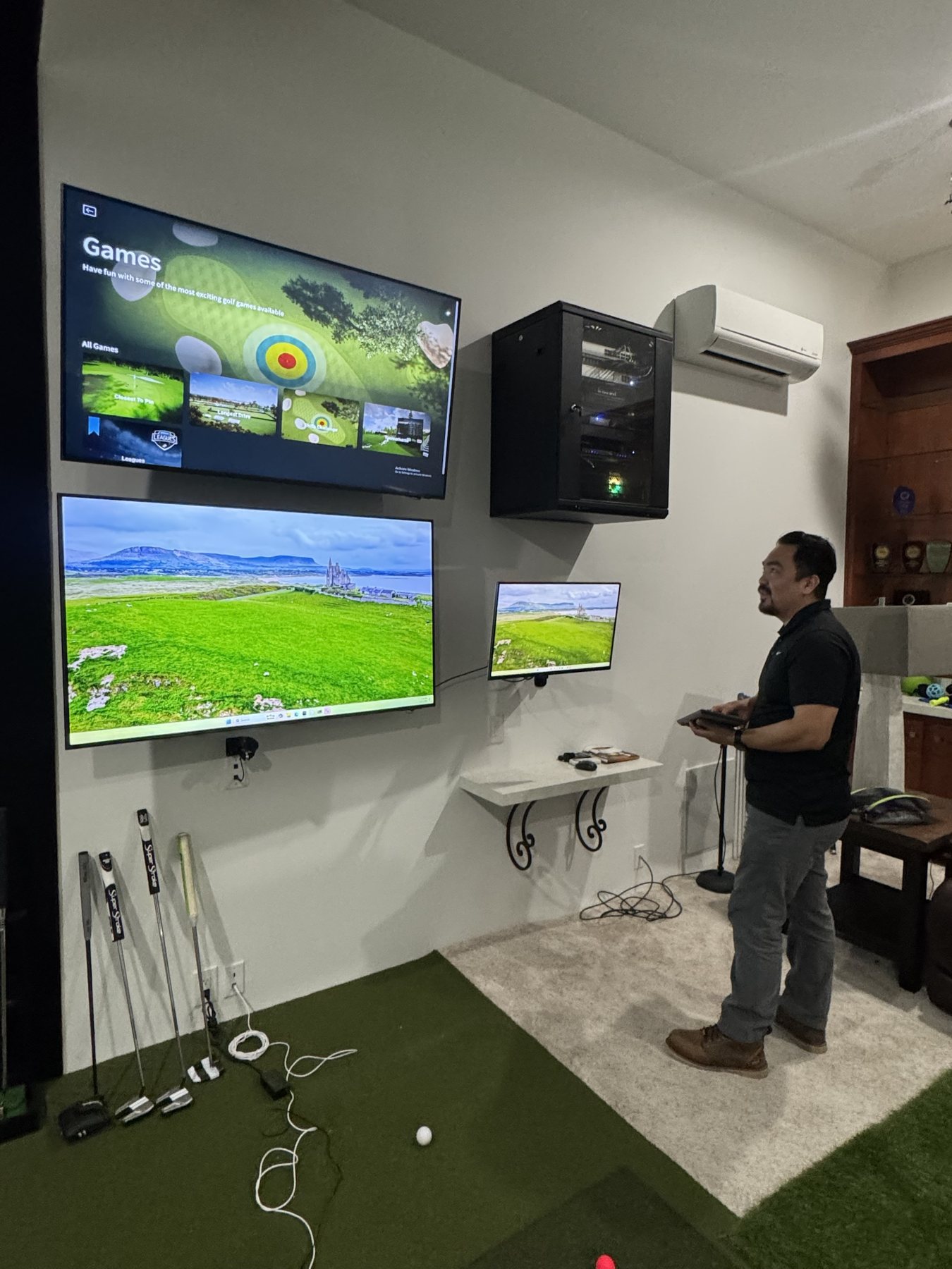 Golf simulator lounge with stacked displays and a wall-mounted equipment rack installed by Itenco