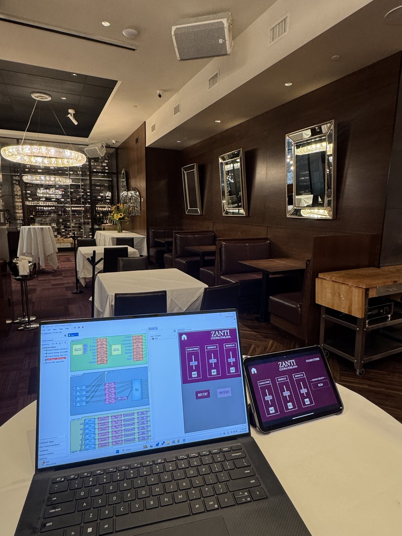 Q-SYS Designer on a laptop beside the tablet zone-control panel Itenco built for Zanti Cucina Italiana